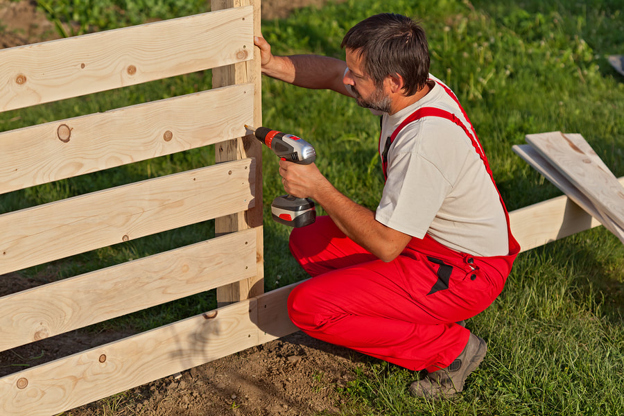 worker installing wood fence